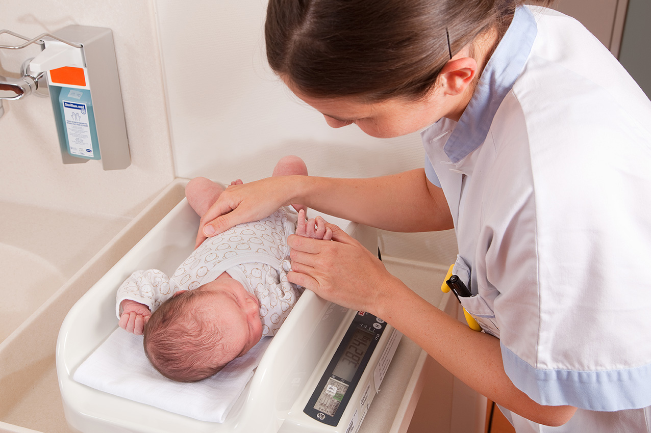 Krankenpflegerin legt Baby auf Waage