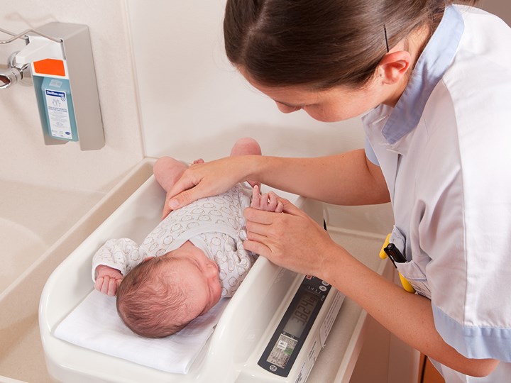 Krankenpflegerin legt Baby auf Waage