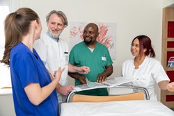 Pflegepersonen am Patientinnen- und Patientenbett im Gespräch