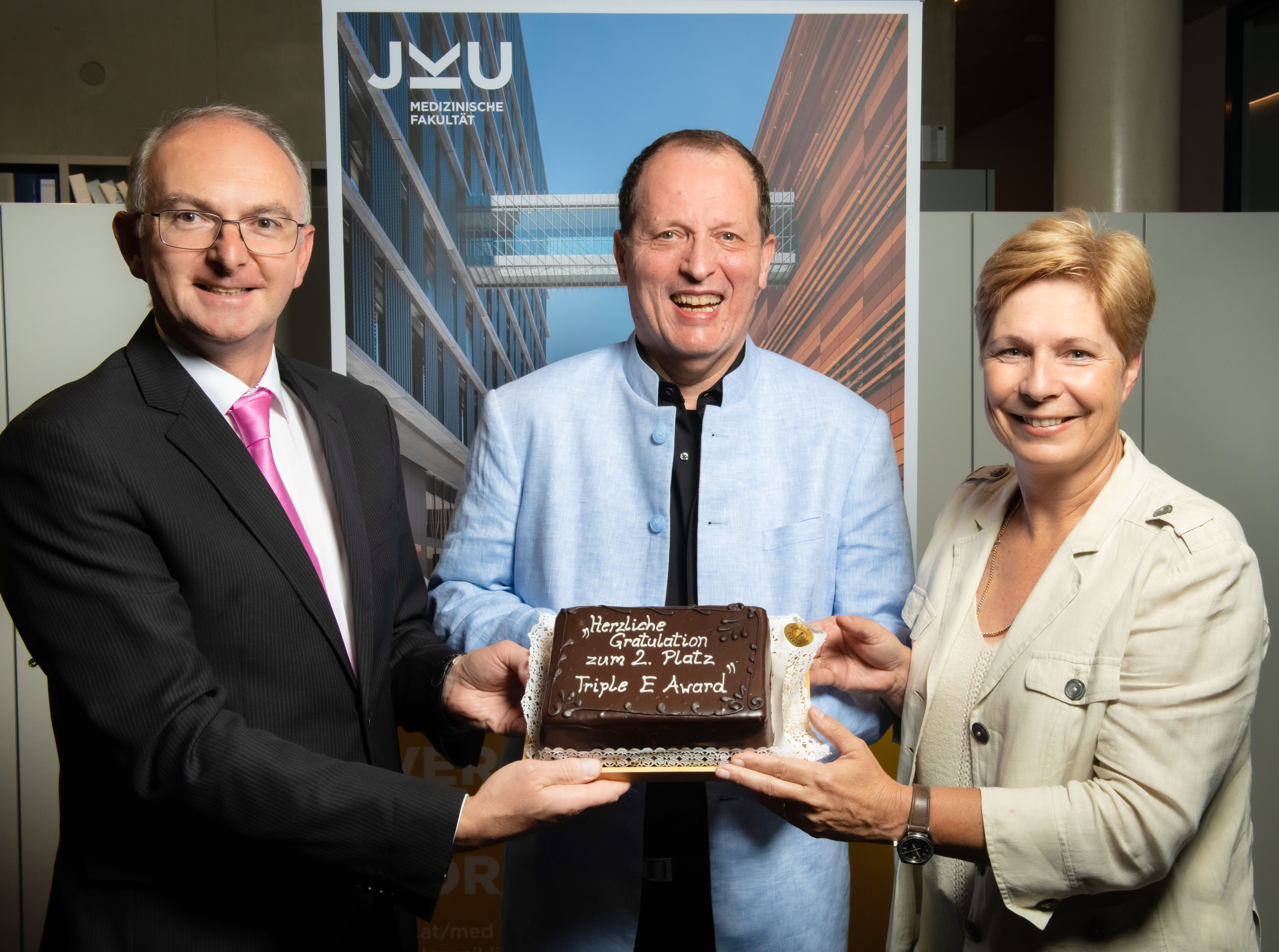 v. l. n. r.: Universitätsprofessor Lamprecht; Professor Fellner, Vizerektorin Drda mit einer Torte anlässlich des Triple E Awards in Silber