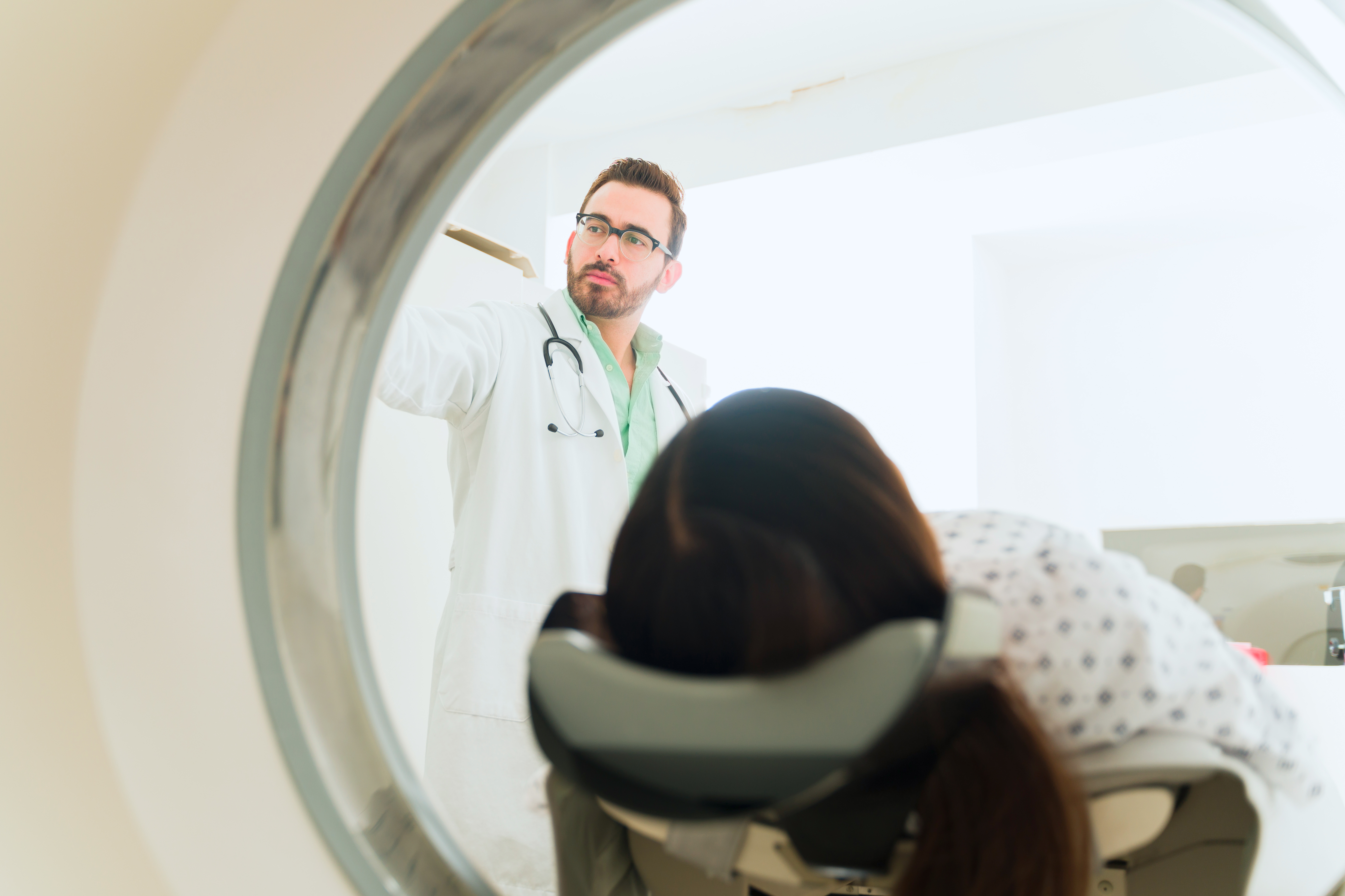 Patientin wird in MR geschoben; im Hintergrund ist ein Arzt sichtbar