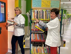 Ehrenamtliche Mitarbeiterinnen mit dem Bücherwagen für die Kinderstationen
