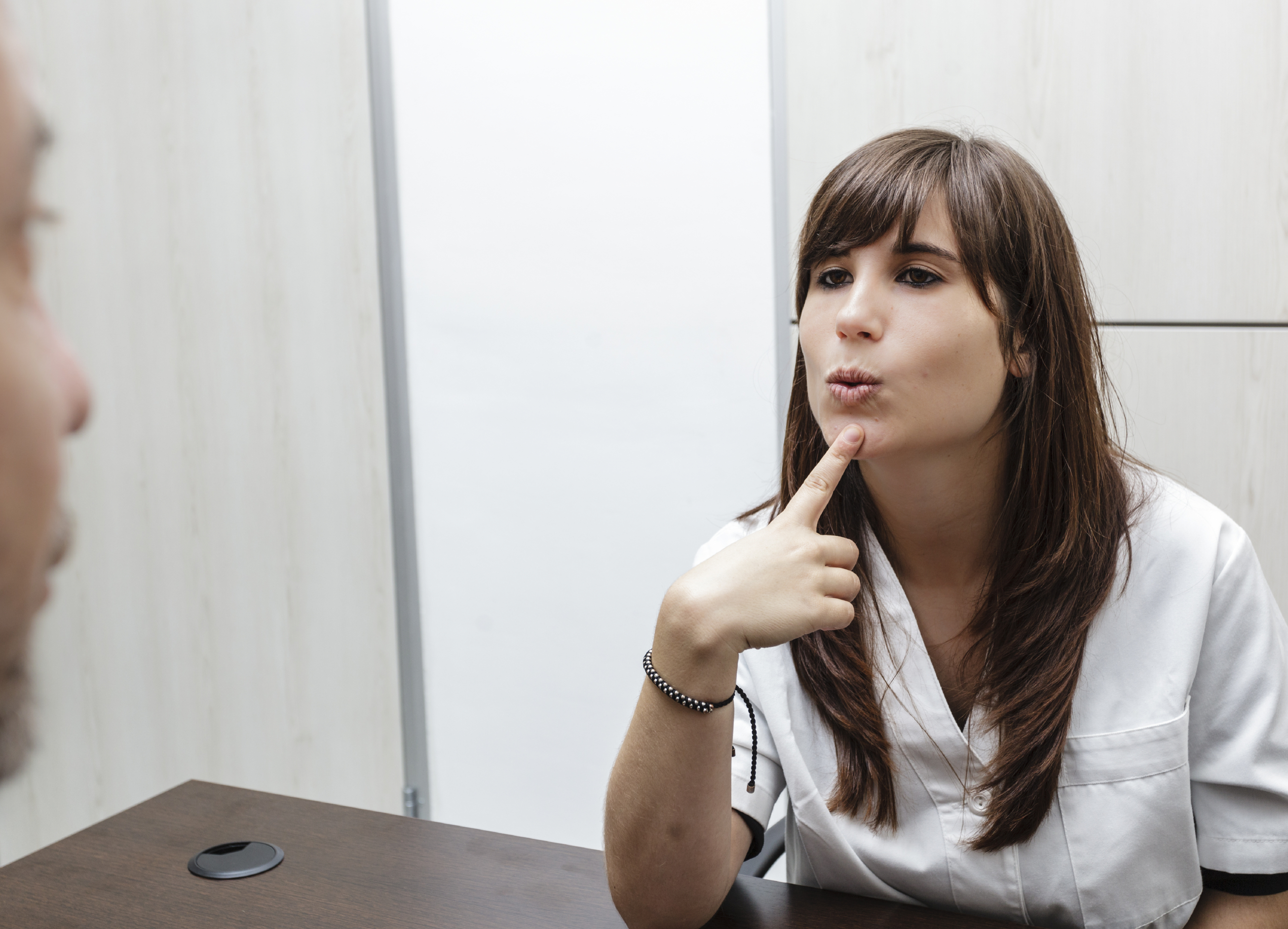 Frau greift sich bei Logopäden mit Finger auf Kinn