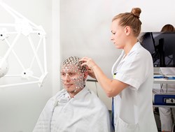 Für die Aufzeichnung eines hochauflösenden EEGs mit 256 Kanälen werden hier die Elektroden von einer biomedizinischen Analytikerin am Kopf des Patienten in Position gebracht.