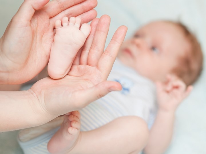 Füße eines Babys werden mit Händen gehalten